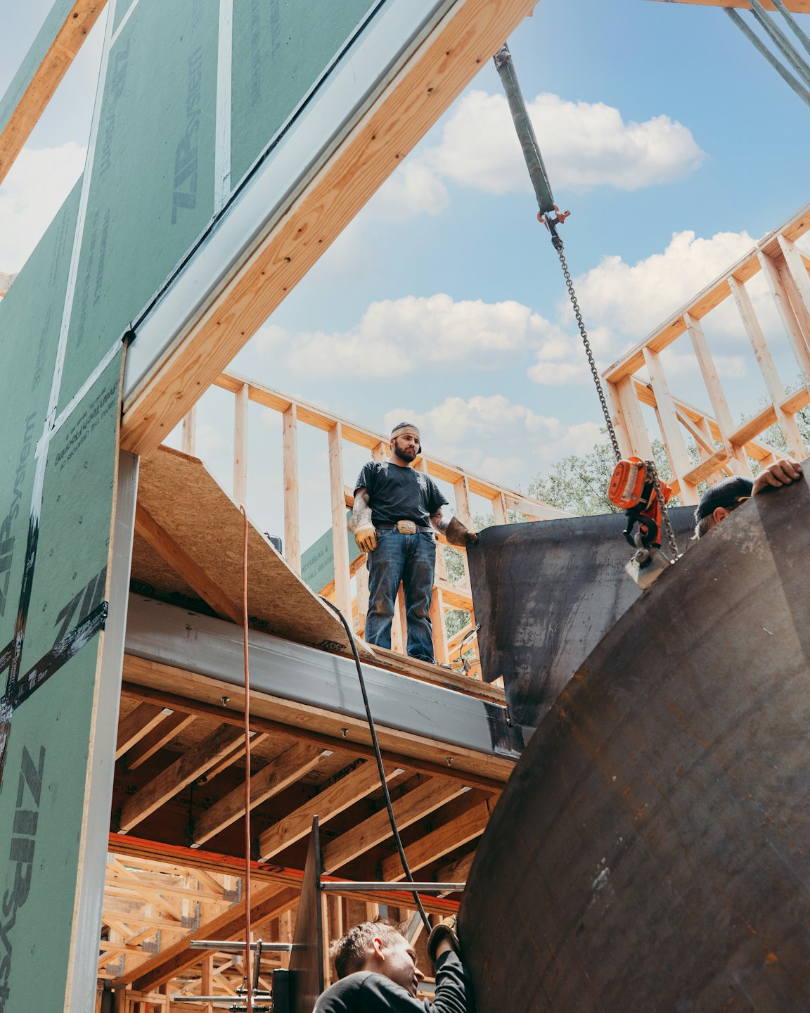 Construction workers lift a metal beam on a building site.