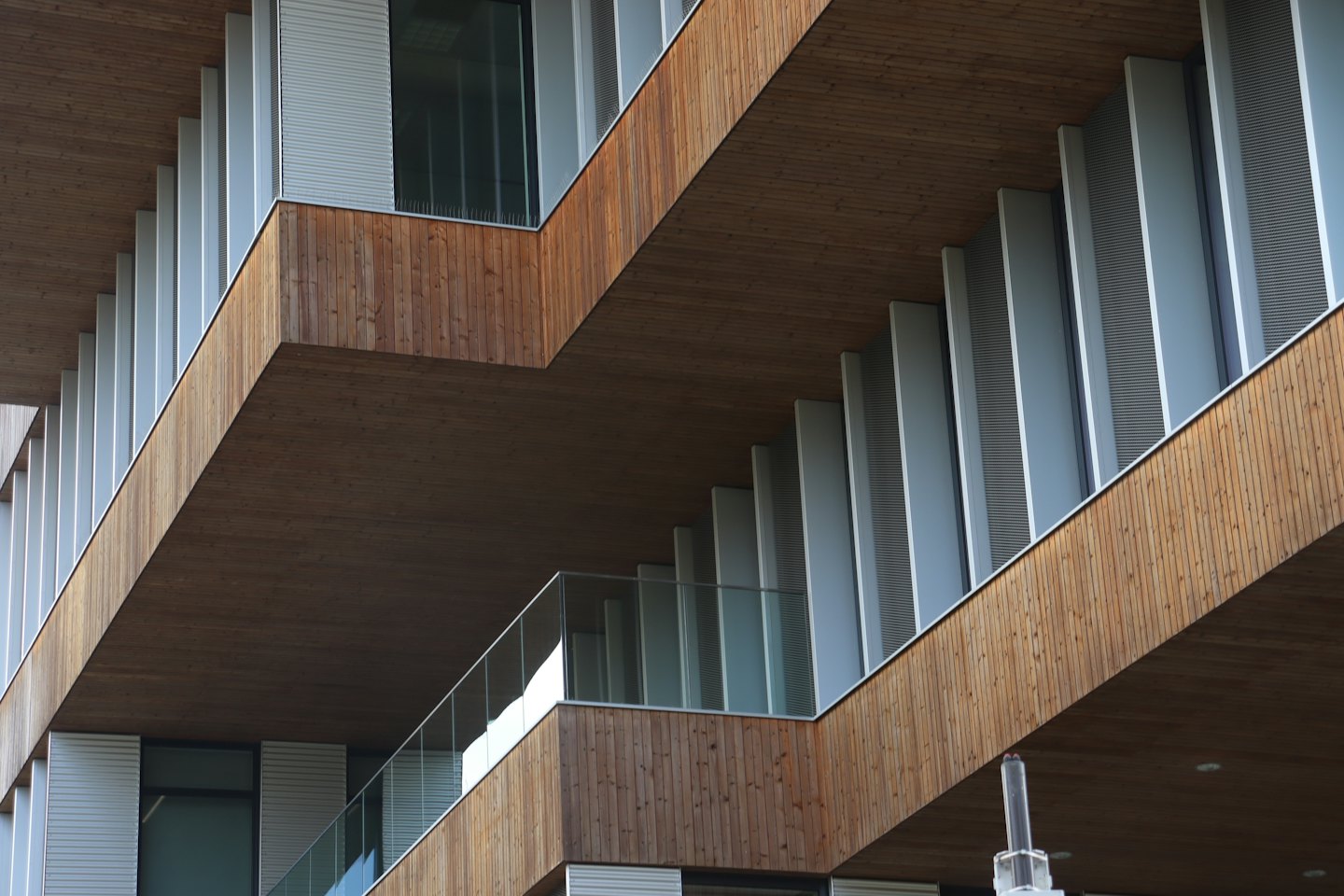 Modern building facade with wooden panels and metal louvers.