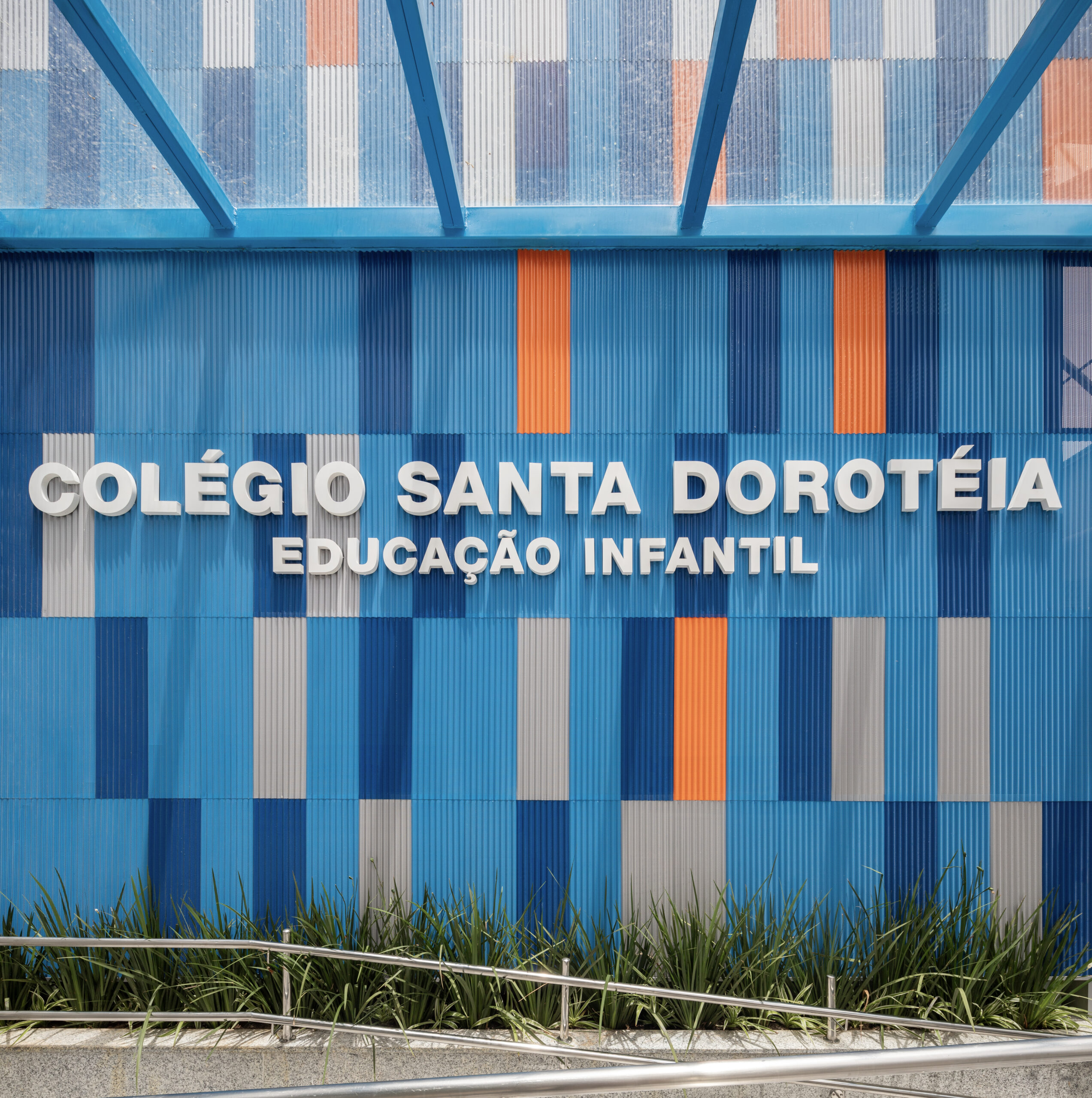 Modern commercial building facade with blue windows and metal panels.