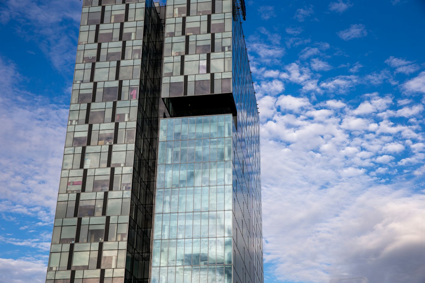 Modern glass skyscraper reaching toward a bright blue sky.